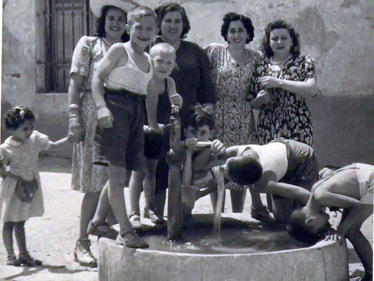 foto antigua blanco y negro años 50 pueblo español. Grupo mujeres y niños refrescándose fuente. Derechos de autor: Junta de Castilla la Mancha