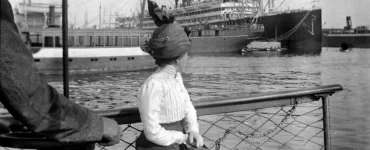 Foto antigua de una mujer sentada en el puertodel Musel con su diario del viaje en la mano. Creative Commons.