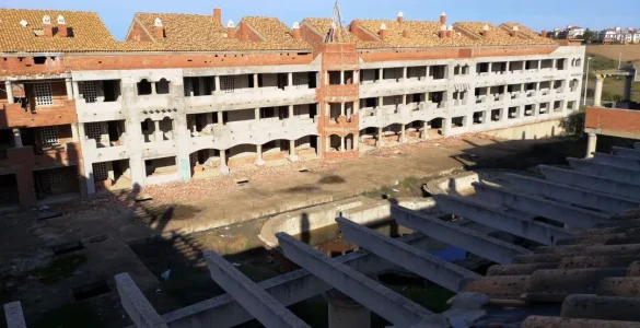 Foto a color de una propiedad en ruinas con muchas casas en abandono, faltan puertas, ventanas y todo cayendo a trozos. Creative Commons atribución 4.0 internacional