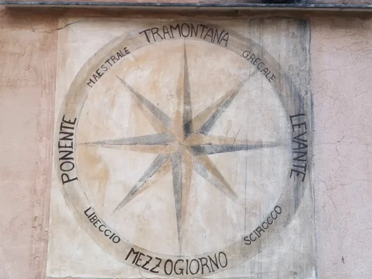 Rosa de los vientos de 8 puntas con nombres de los vientos en italiano dibujada en el muro de una casa en San Felice Circeo