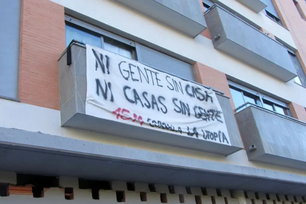 Pancarta de un bloque ocupado en Sevilla por familias de trabajadores. En la pancarta se lee: ni gente sin casas ni casas sin gente