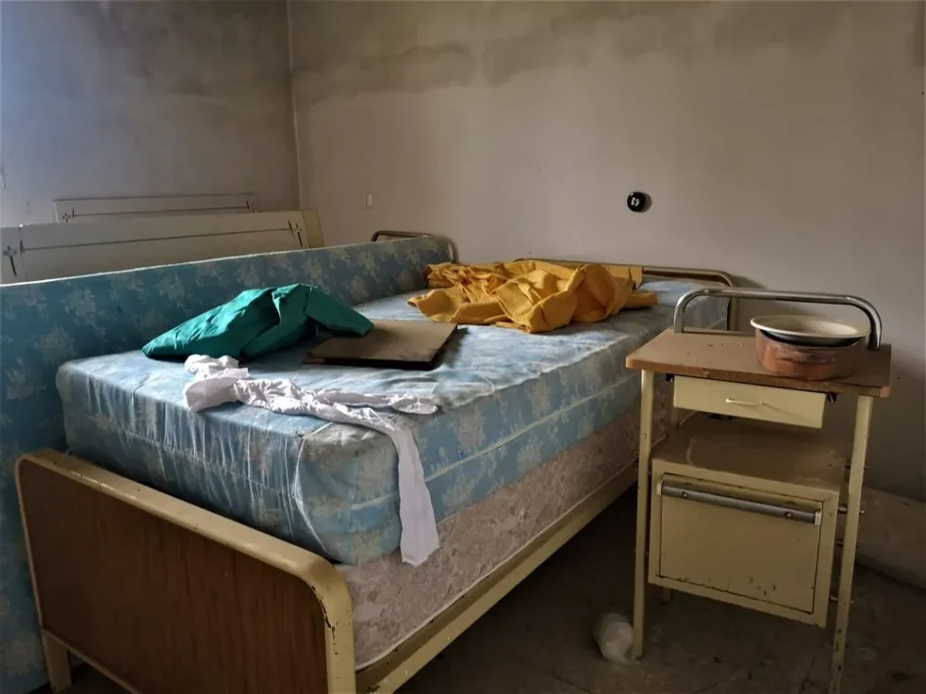 Cama con colchón, ropa y orinal al lado en el Instituto Leprológico Nacional de Trillo. Leprosería de Trillo, un lugar de curación vuelto ruina