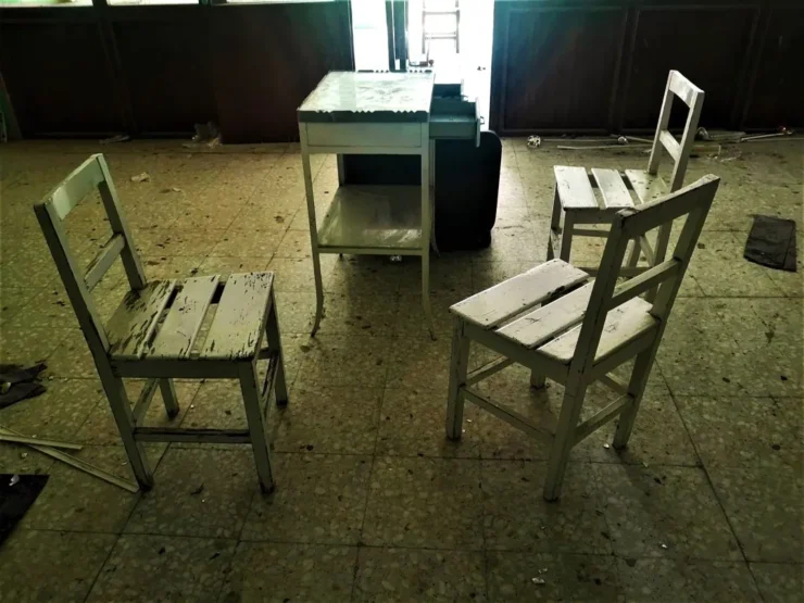 Sillas alrededor de una mesa en una sala del Instituto Leprológico Nacional de Trillo, mostrando el estado de abandono del lugar.
