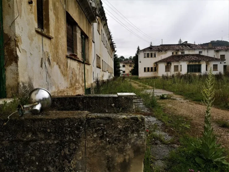 Edificios y patios llenos de maleza en la Leprosería de Trillo, mostrando el abandono de este lugar histórico. Autor: Viaje a Edén