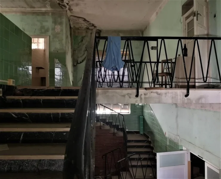 Escaleras con una bata colgando de la barandilla en el Instituto Leprológico Nacional de Trillo, reflejo del abandono del lugar
