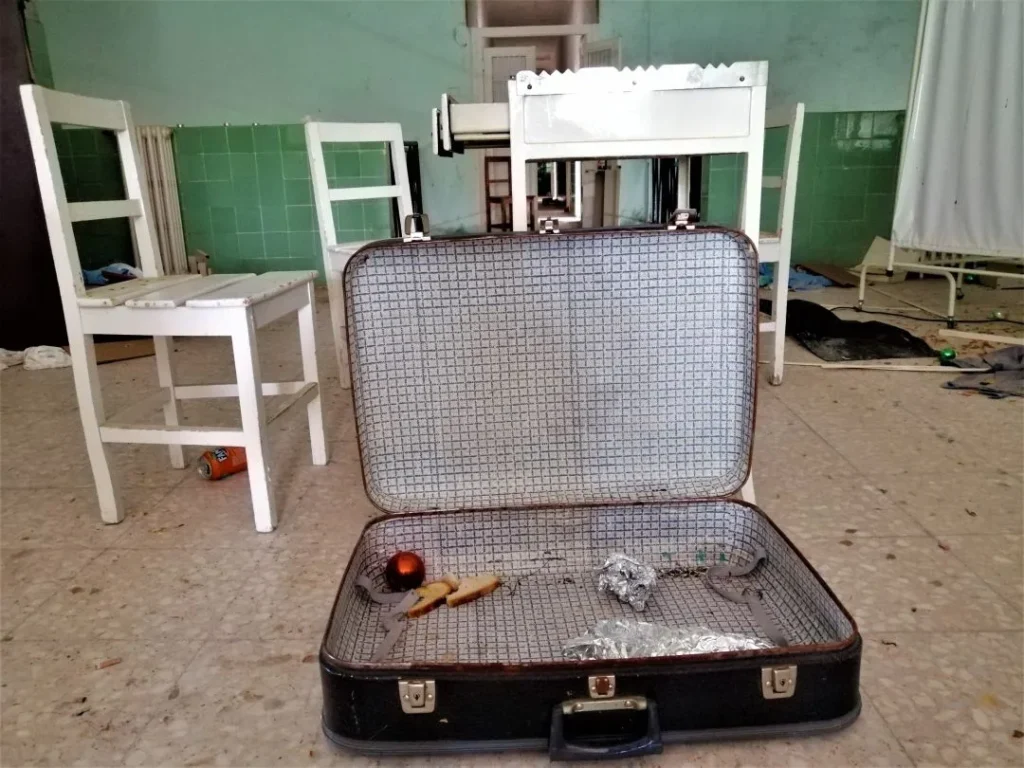 Maleta con restos de comida y sillas de fondo en el Instituto Leprológico Nacional de Trillo. Leprosería de Trillo, un lugar de curación vuelto ruina