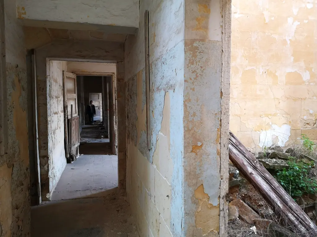 Exploradora al final del pasillo en el edificio norte del Palacio Nuevo del Lazareto de Malta, mostrando su arquitectura