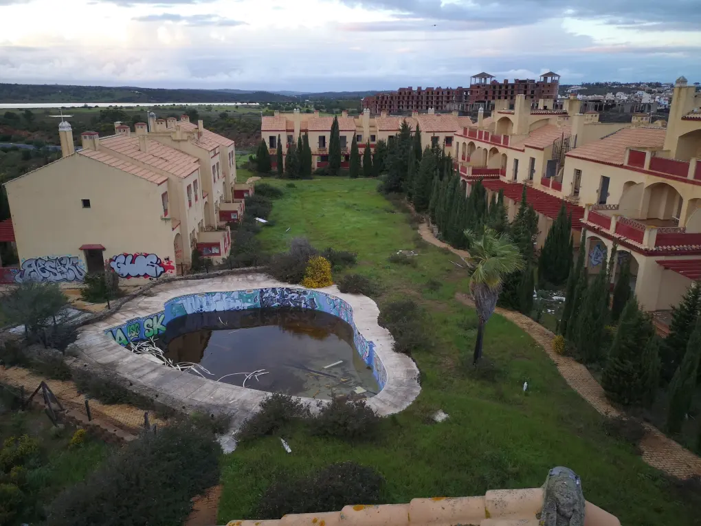 Casas abandonadas con piscina en ruinas en Costa Esuri, Ayamonte; paisaje desolado que evoca un pasado detenido en el tiempo