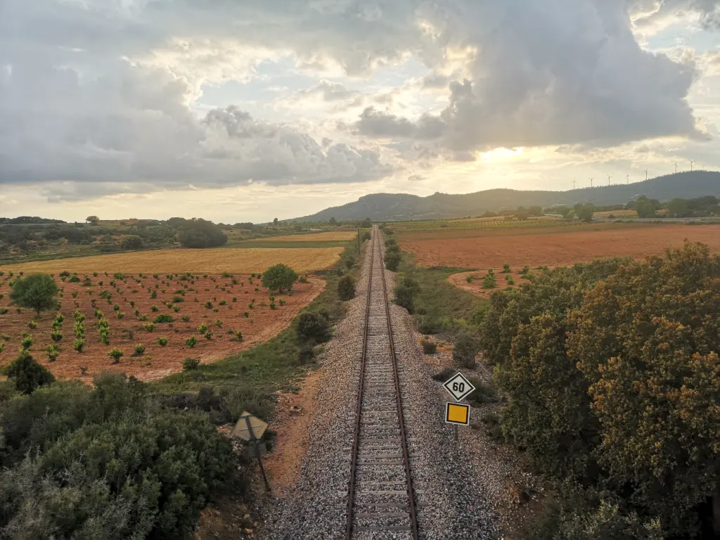ferrocarril cruzando una extensa llanura, al fondo montañas