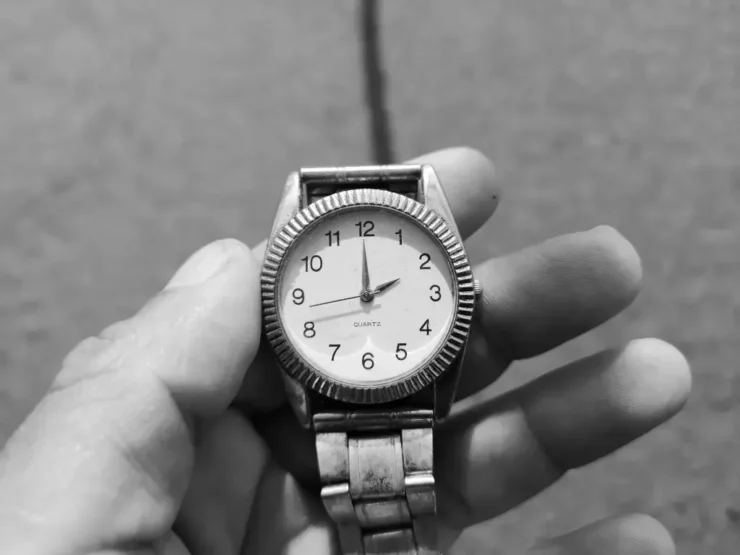 Una mano sujeta un reloj después de adaptar la hora local. Paso 1 y 2 orientarse con un reloj y el sol a la UTC