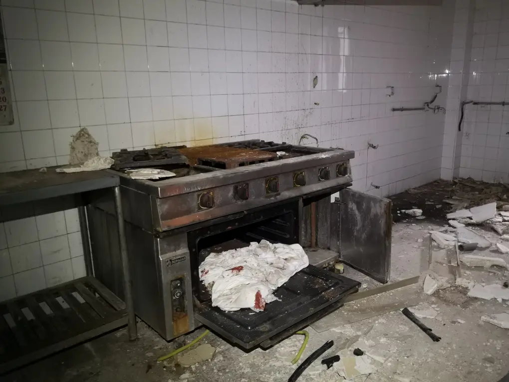 Horno ennegrecido y oxidado en la cocina del albergue Luis Arias, Puerto de navacerrada. La cocina está en ruinas y todo por los suelos.
