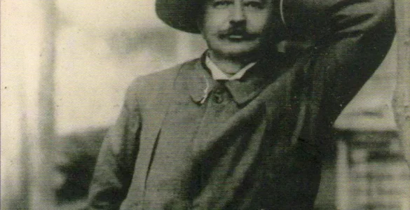 Retrato en blanco y negro de Iñigo Noriega Laso. Lleva un sombrero, el codo apoyado en un muro y sonríe a la cámara