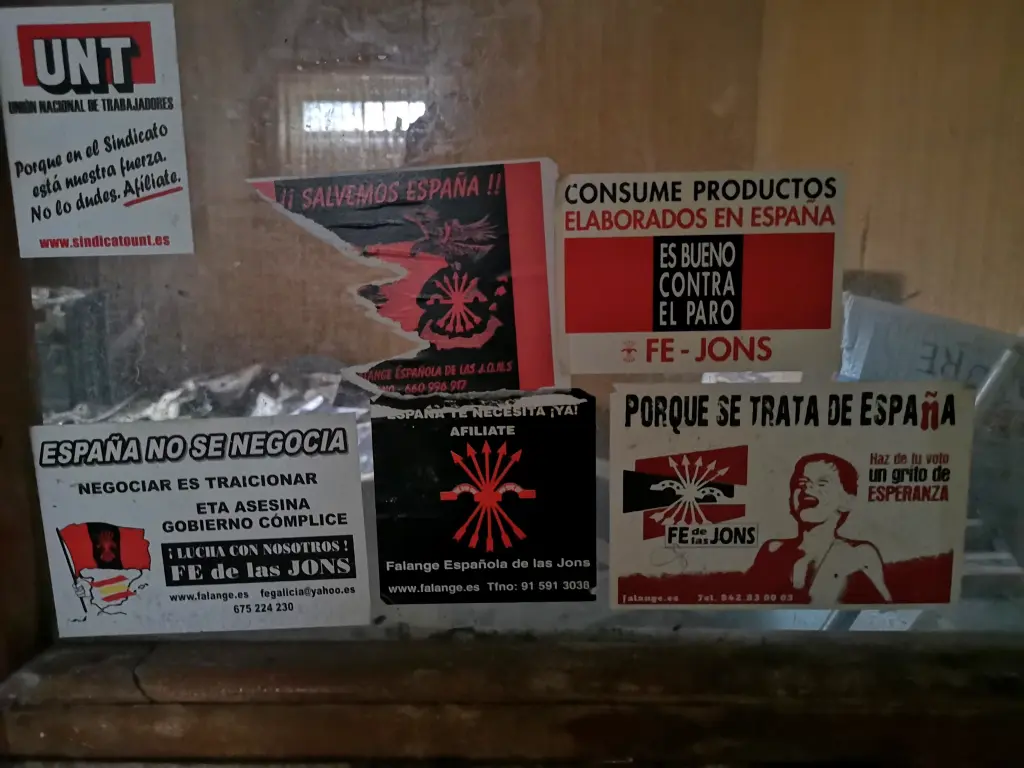 Primer plano de la puerta del despacho de la Sede de Falange de Los Corrales de Buelna, repleta de pegatinas políticas