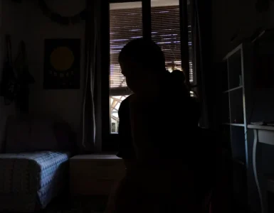 Joven mujer ensimismada sentada en el medio de un cuarto en penumbra