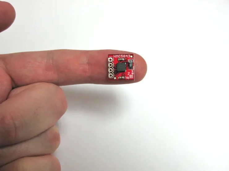 Dedo de una mano sobre fondo blanco sosteniendo un chip magnético