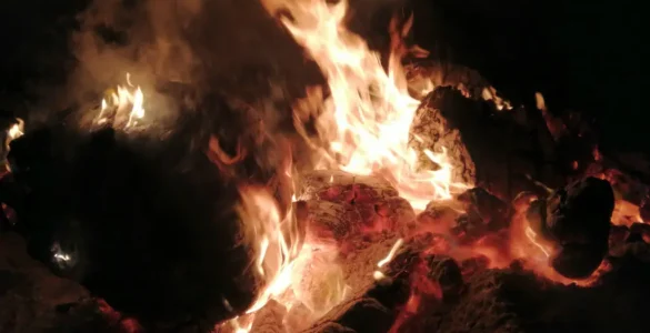 Primer plano de una hoguera en la noche de San Juan. Se distinguen perfectamente las llamas y los tajos de madera