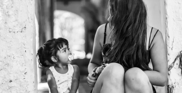 Una madre u una hija se miran, parecen que la madre le está diciendo algo y la niña escucha atenta.