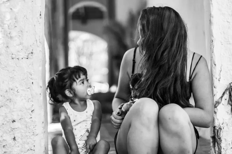 Una madre u una hija se miran, parecen que la madre le está diciendo algo y la niña escucha atenta.