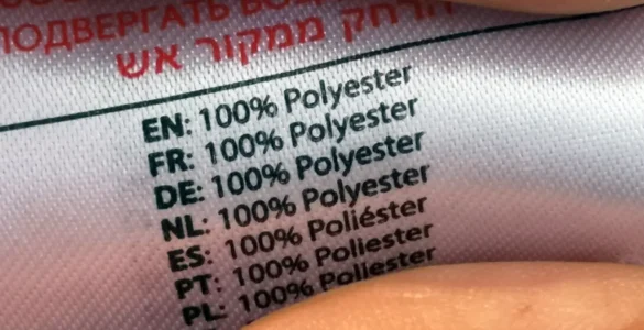 Primer plano de una etiqueta de ropa 100% poliester entre dos dedos