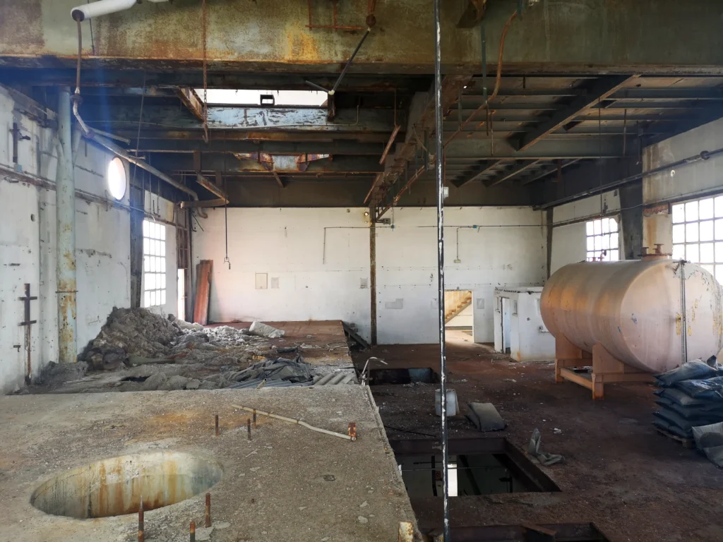 Nave del edificio de HCH de inquinosa, con tanque, base de cemento para maquinara y desechos tóxicos al fondo