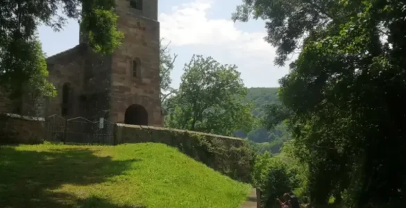 Un viajero cruza el camino en frente de la Iglesia de San Miguel de Pesquera de Reinosa