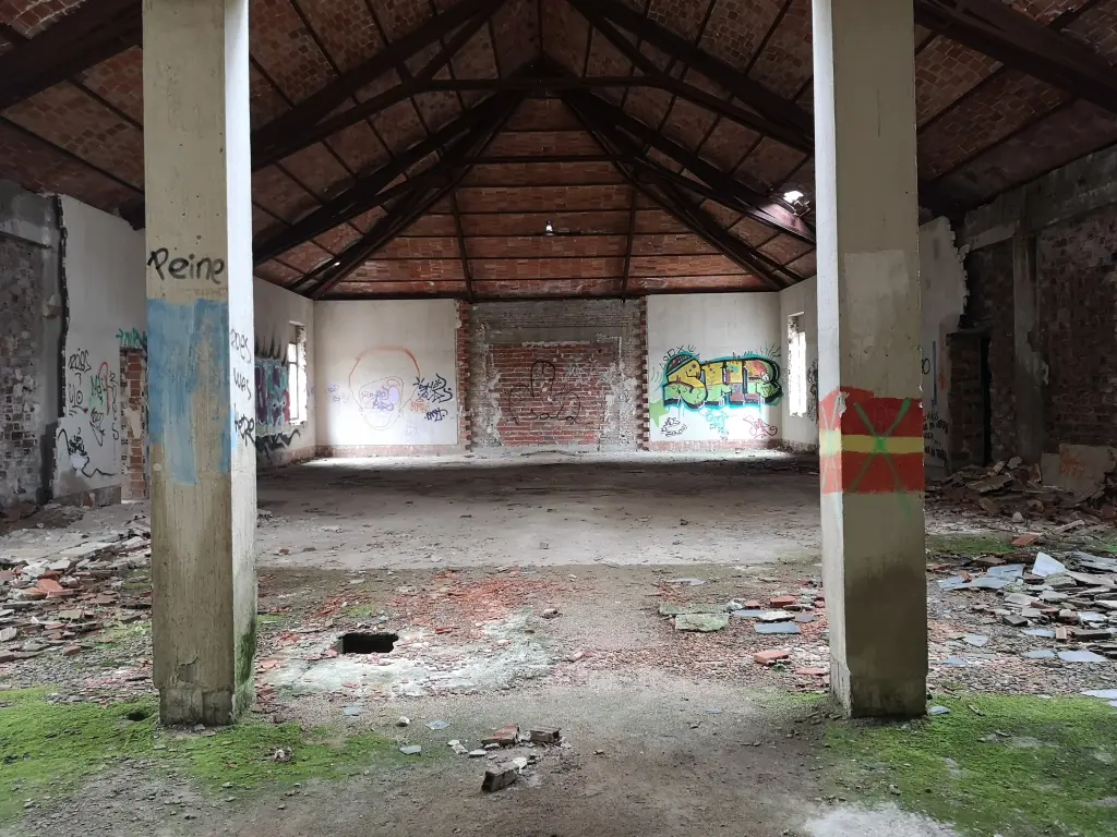 dificio principal del sanatorio abandonado de Tablada: buhardilla con escombros, pilares visibles, grafitis y techos de ladrillo expuesto