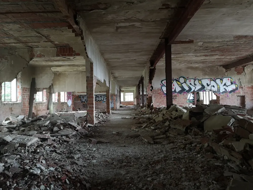Interior en ruinas del sanatorio de Tablada: escombros, grafitis y techos deteriorados en un ala lateral del edificio
