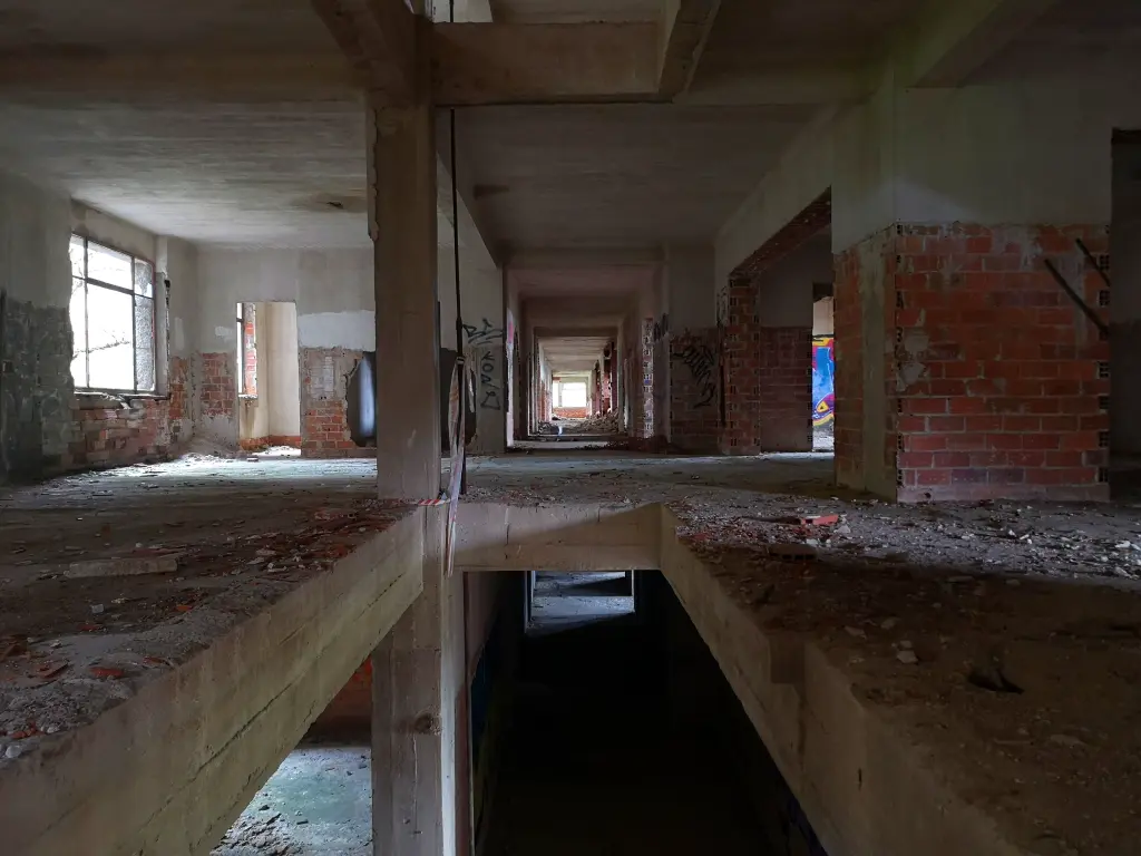 Interior sanatorio de Tablada, planta mediana: pasillo en ruinas, con aberturas en el suelo y paredes de ladrillo a la vista