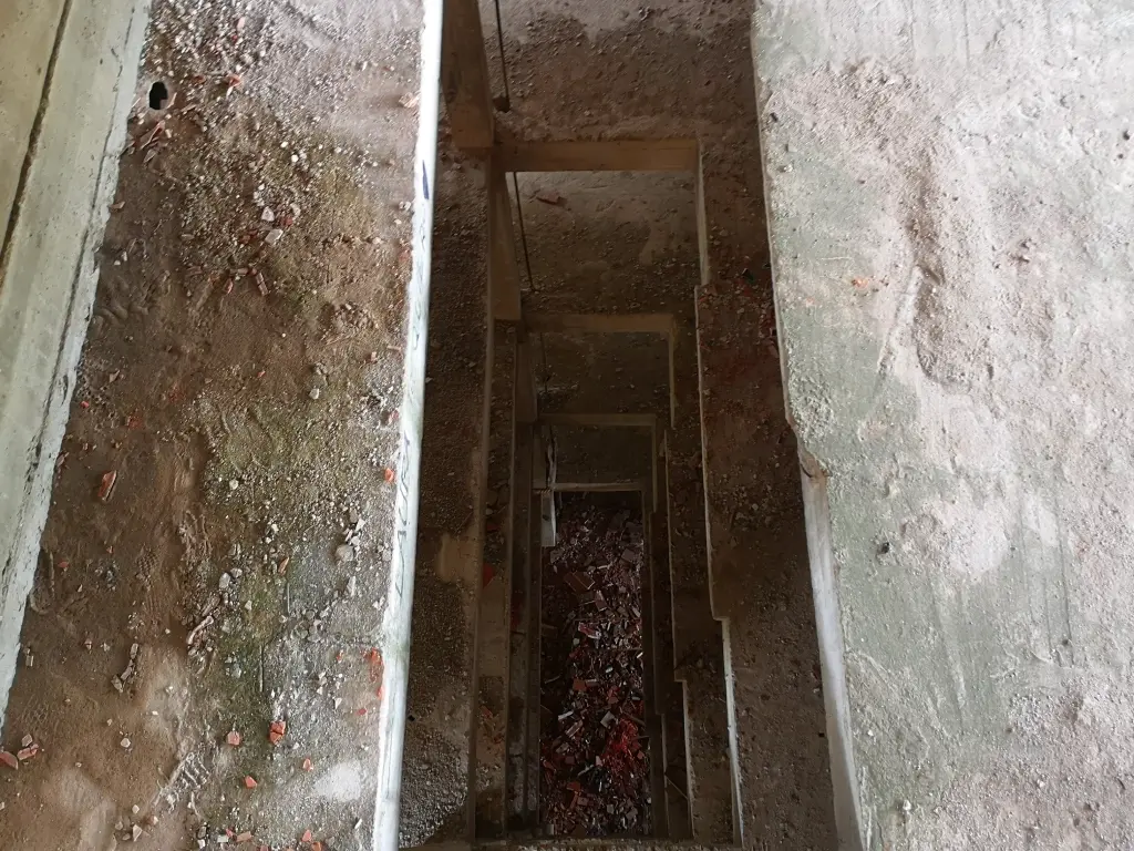 Abertura vertical en el suelo de varios pisos del sanatorio abandonado de Tablada, posiblemente diseñada para ventilación o entrada de luz natural, con escombros acumulados en el fondo