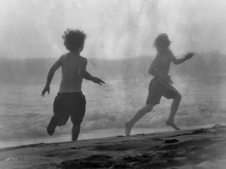 Pensamiento Nómada: Niños jugando a pilla pilla en la orilla del mar, representando la acción, el movimiento y la experiencia libre del conocimiento