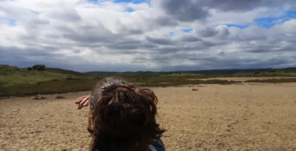 una mujer viajera mirando al horizonte como metodo de orientacion sin brujula, está buscando camino en un entorno natural