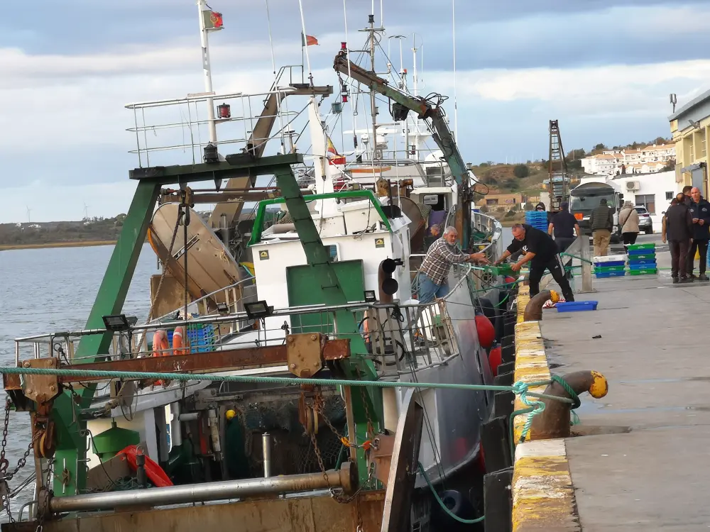 Barco de pesca de arrastre amarrado en el puerto de Ayamonte. Casi al fondo se notan dos marineros desembarcando cajas de pescado