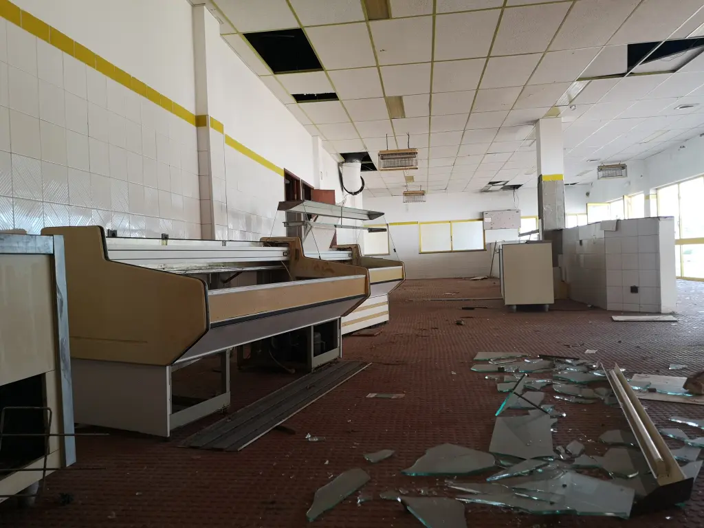 Interior de la cafetería del parque acuático Aqualine, actualmente abandonado y en ruinas en Castro Marín, Portugal, con mobiliario deteriorado, paredes desconchadas y signos visibles de abandono.