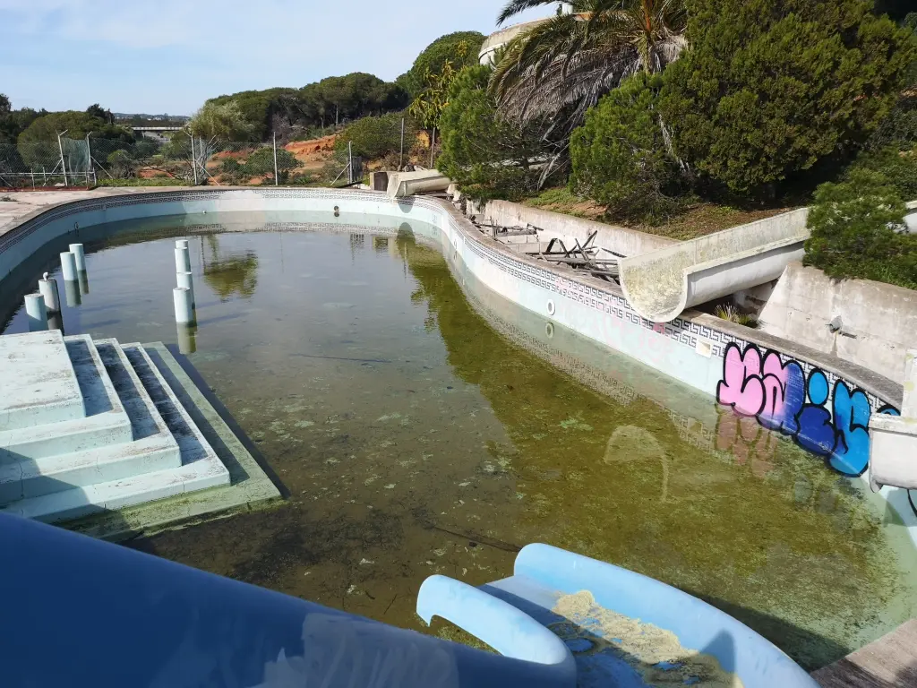 piscina infantil con agua estancada y estructuras deterioradas, en el parque acuático abandonado de Castro Marín en Portugal.