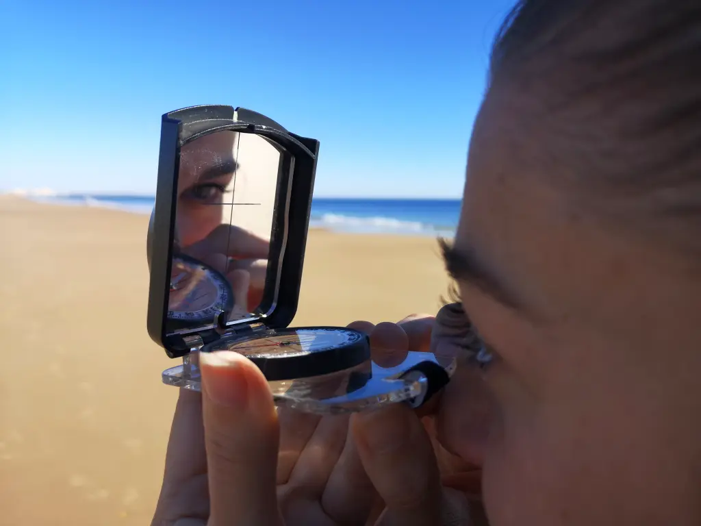Carmen utilizando el sistema de mira de una brújula de espejo durante una ruta costera